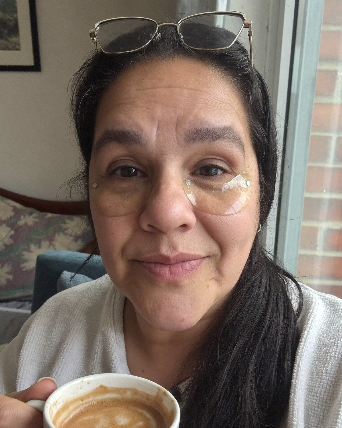 Mujer con los parches de ojos puestos tomando un café